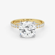 Gold ring with a large diamond and smaller diamonds on the band, on a white background.