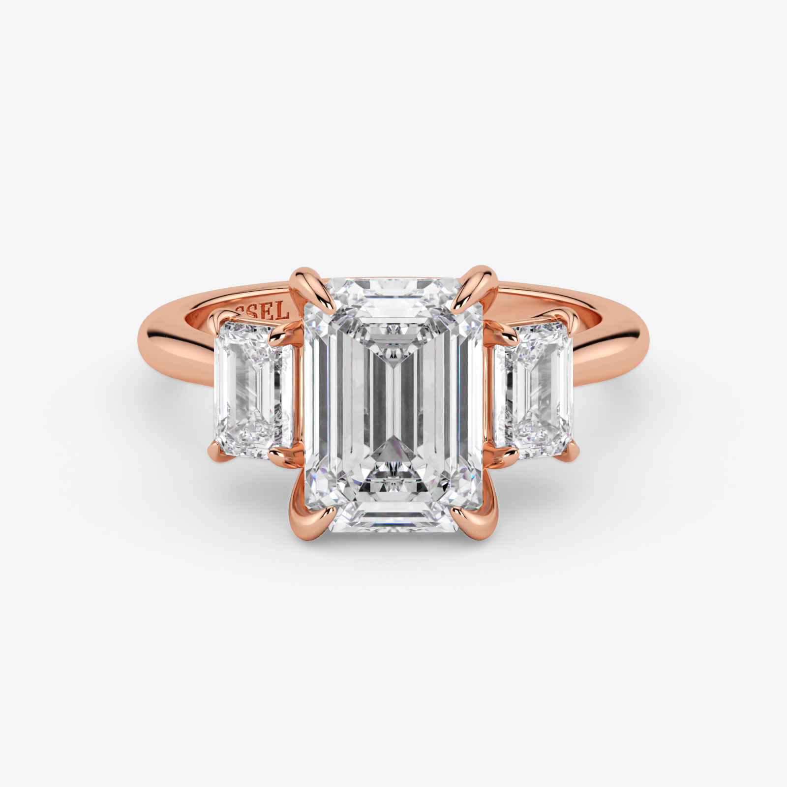 Rose gold ring with emerald-cut diamond and baguette side stones on a white background