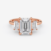 Rose gold ring with emerald-cut diamond and baguette side stones on a white background