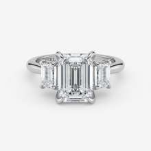 Diamond ring with emerald-cut stones on a white background