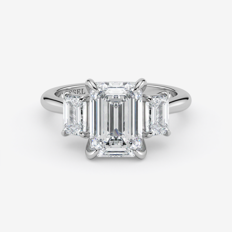 Diamond ring with emerald-cut stones on a white background