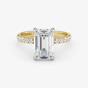 Gold ring with a large diamond and smaller diamonds on the band against a white background