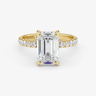 Gold ring with emerald-cut diamond and smaller diamonds on a white background
