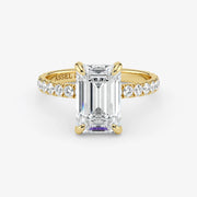Gold ring with emerald-cut diamond and smaller diamonds on a white background