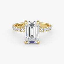 Gold ring with emerald-cut diamond and smaller diamonds on a white background