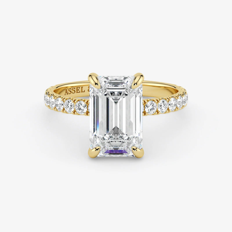 Gold ring with emerald-cut diamond and smaller diamonds on a white background
