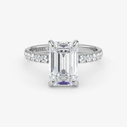 Diamond ring with emerald-cut center stone on a white background