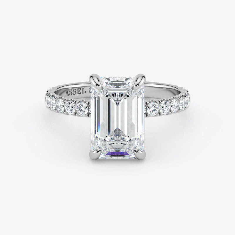 Diamond ring with emerald-cut center stone on a white background