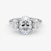 Diamond ring with a central oval-cut diamond and two smaller diamonds on a white background