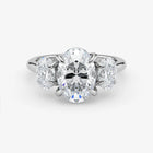 Diamond ring with a central oval-cut diamond and two smaller diamonds on a white background