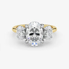 Diamond ring with a central oval-cut diamond flanked by two round-cut diamonds on a white background