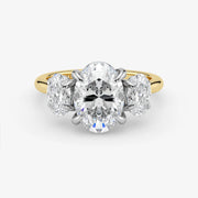 Diamond ring with a central oval-cut diamond flanked by two round-cut diamonds on a white background