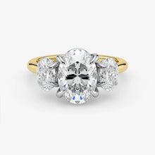 Diamond ring with a central oval-cut diamond flanked by two round-cut diamonds on a white background