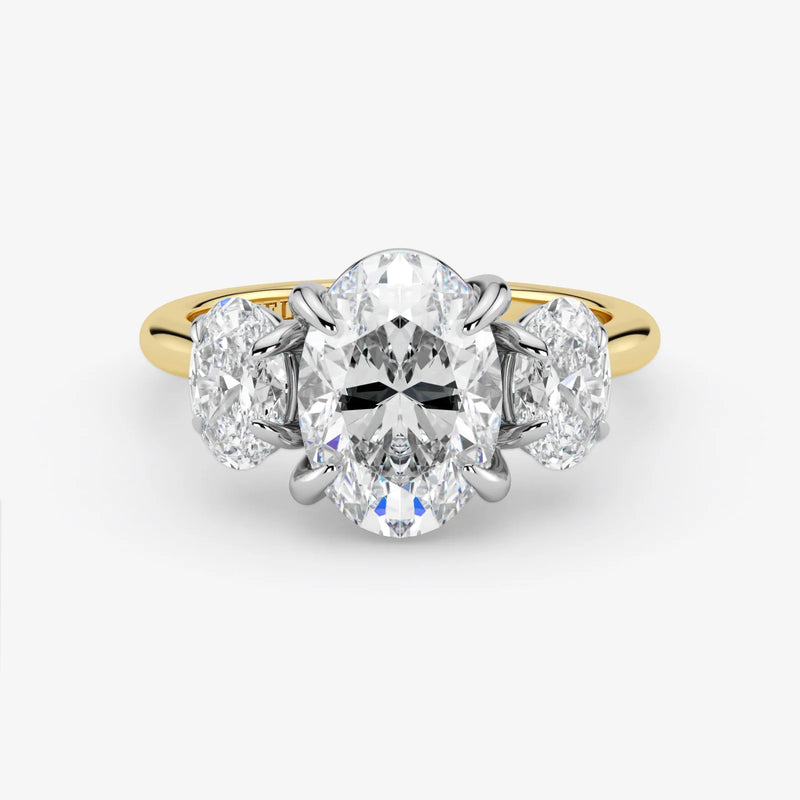 Diamond ring with a central oval-cut diamond flanked by two round-cut diamonds on a white background