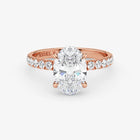 Rose gold ring with a large diamond and smaller diamonds on the band against a white background