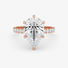 Rose gold ring with a large diamond and smaller diamonds on the band against a white background
