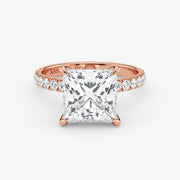 Rose gold ring with a large diamond and smaller diamonds on the band against a white background