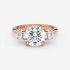 Rose gold ring with a large diamond and two smaller diamonds on a white background