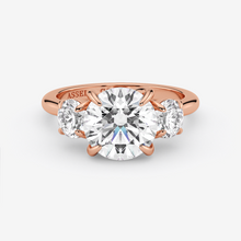 Rose gold ring with a large diamond and two smaller diamonds on a white background