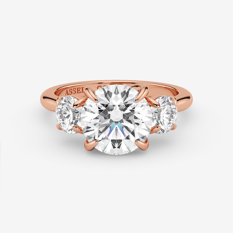 Rose gold ring with a large diamond and two smaller diamonds on a white background