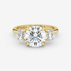 Gold ring with a large diamond and two smaller diamonds on a white background