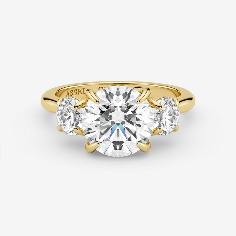 Gold ring with a large diamond and two smaller diamonds on a white background