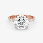 Rose gold ring with a large diamond and smaller diamonds on the band against a white background