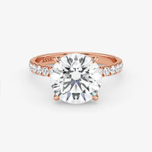 Rose gold ring with a large diamond and smaller diamonds on the band against a white background