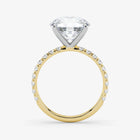 Gold ring with a large diamond and smaller diamonds on the band against a white background