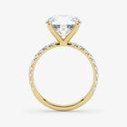 Gold ring with a large diamond and smaller diamonds on the band against a white background