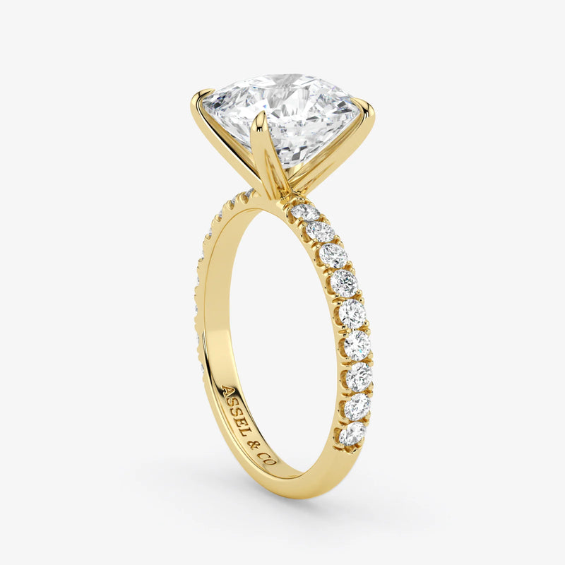 Gold ring with a large diamond and smaller diamonds on the band against a white background