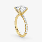 Gold ring with a large diamond and smaller diamonds on the band against a white background