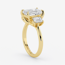 Gold ring with two emerald-cut diamonds on a white background