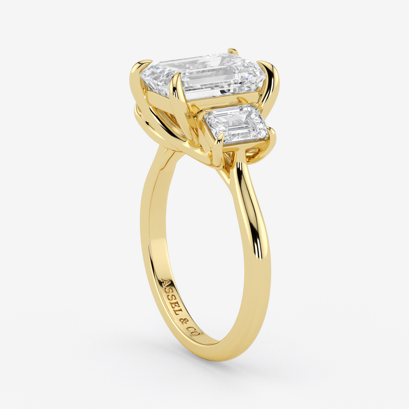 Gold ring with two emerald-cut diamonds on a white background