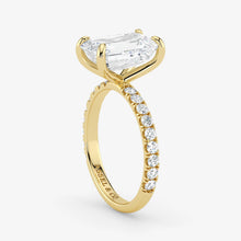 Gold ring with a large diamond and smaller diamonds on the band against a white background