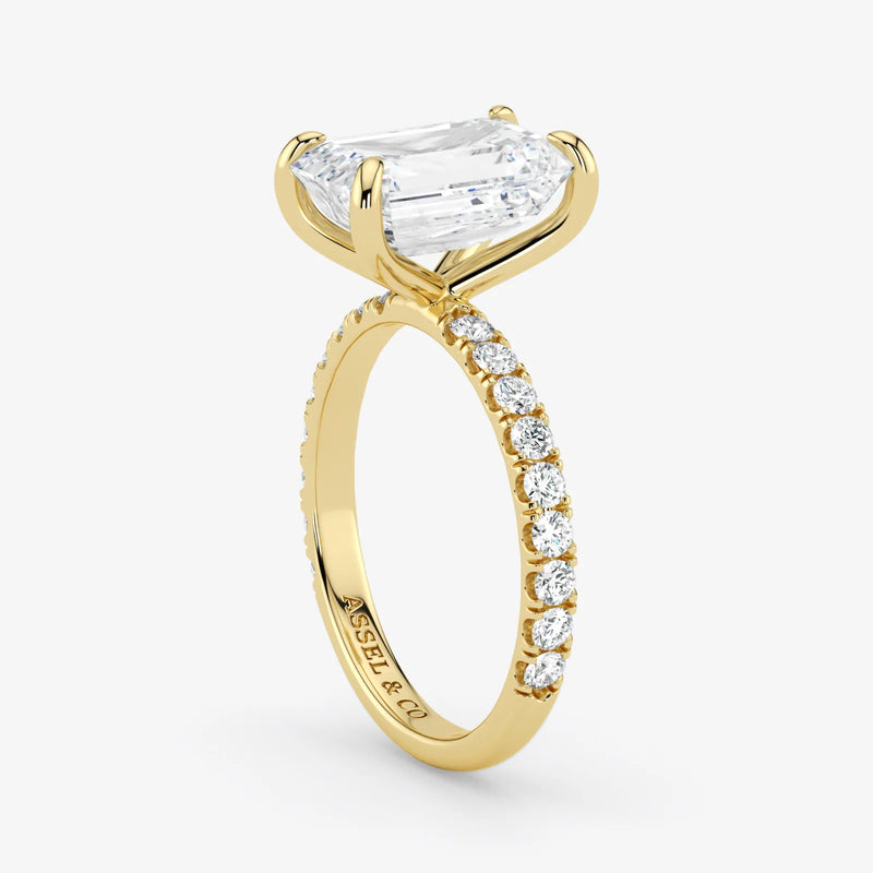 Gold ring with a large diamond and smaller diamonds on the band against a white background