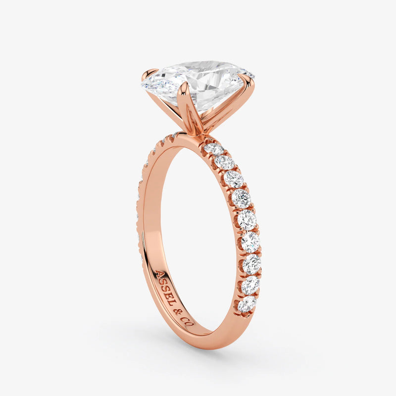 Rose gold ring with a large diamond and smaller diamonds on the band against a white background