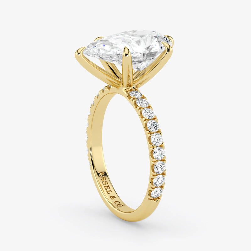 Gold ring with a large diamond and smaller diamonds on the band against a white background