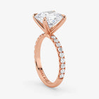 Rose gold ring with a large diamond and smaller diamonds on the band against a white background