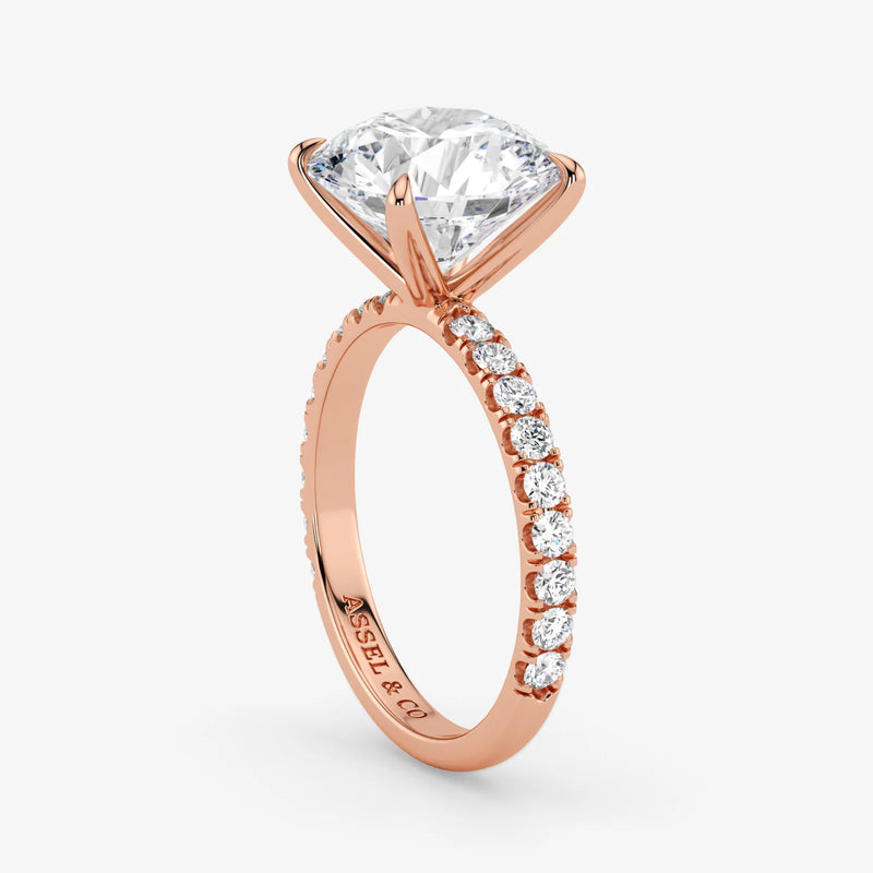 Rose gold ring with a large diamond and smaller diamonds on the band against a white background