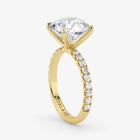 Gold ring with a large diamond and smaller diamonds on the band against a white background