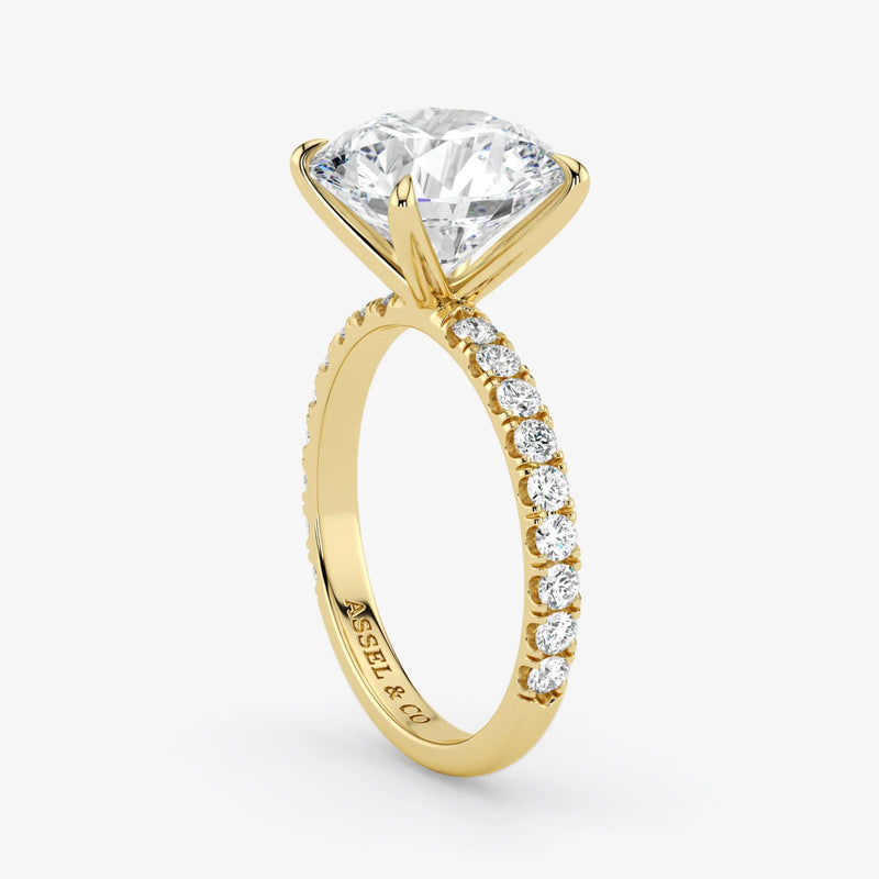 Gold ring with a large diamond and smaller diamonds on the band against a white background